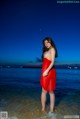A woman in a red dress standing in the water.